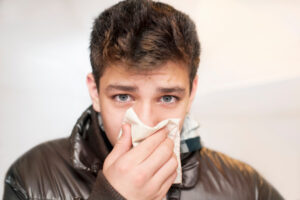 young adult holding handkerchief over mouth