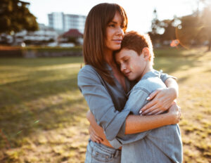 mom and son embracing in middle of park