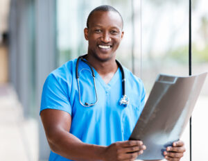 man in doctor scrubs looking at camera and holding xray print